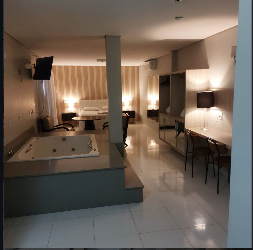 Suíte ampla do hotel com hidromassagem, bancada de trabalho e iluminação aconchegante